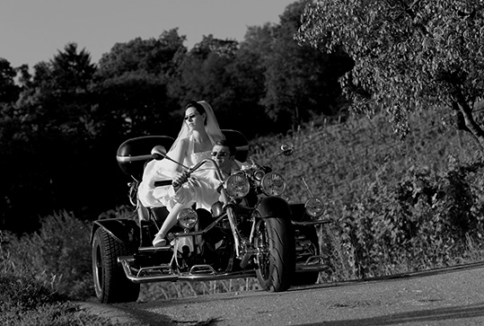 Das Brautpaar fährt auf einem Tribike durch die Weinberge. Hochzeitsfotograf in Weinheim.