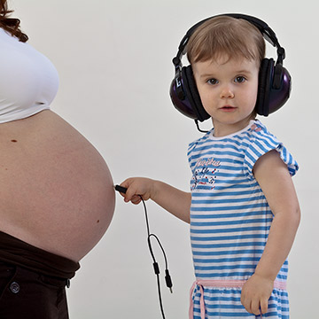 Das Kind mit den Kopfhörern und Babybauch