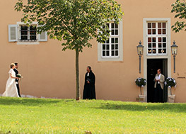 Das Brautpaar nähert sich zu Kirche. Der Priester steht davor und wartet